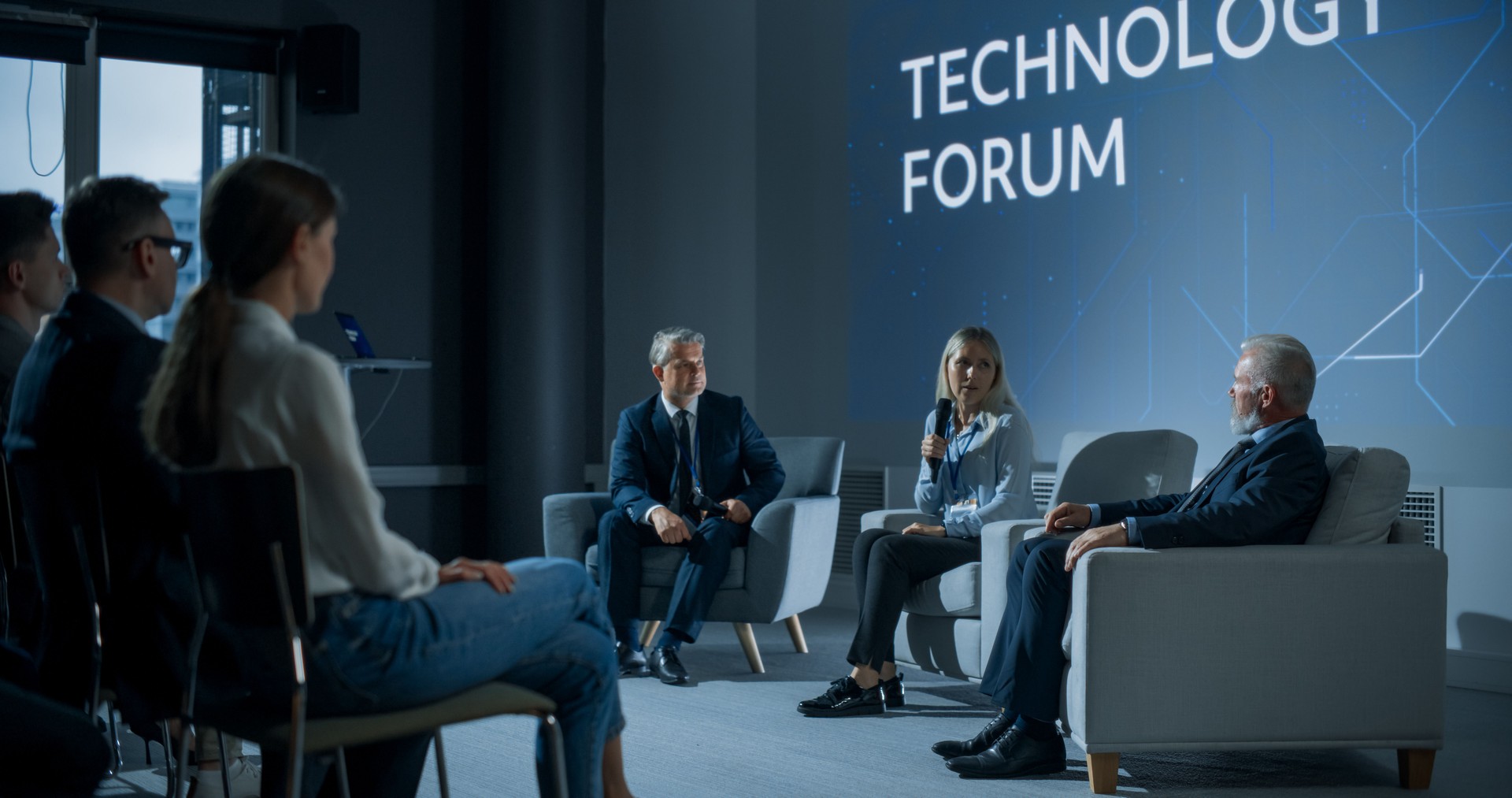 International Technology Conference: Male Host Asking Caucasian Female CEO a Question In Front Of Audience. Successful Woman Delivering Inspirational Speech And Diverse Attendees Listening Carefully.
